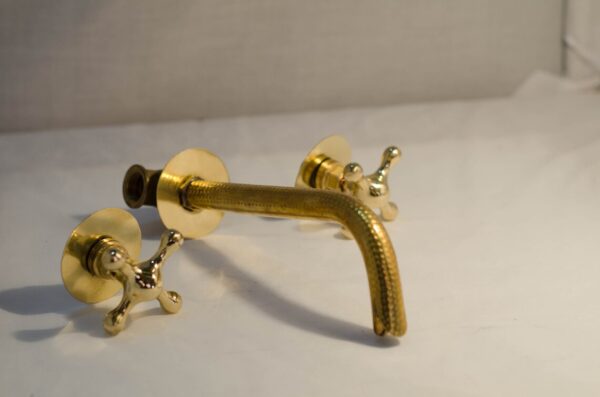 Bathroom sink faucet with an unlacquered brass design, wall-mounted